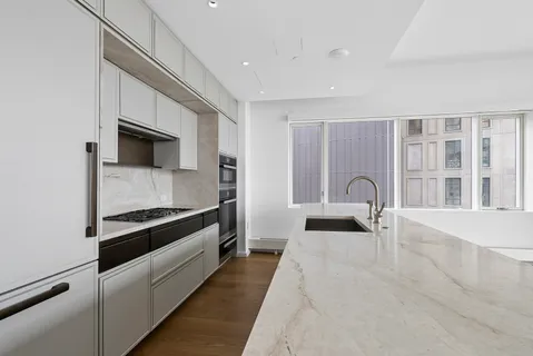 a large white kitchen with granite countertop a stove and a sink with granite countertops