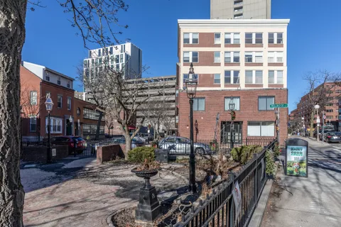 a front view of a building with lot of cars and trees