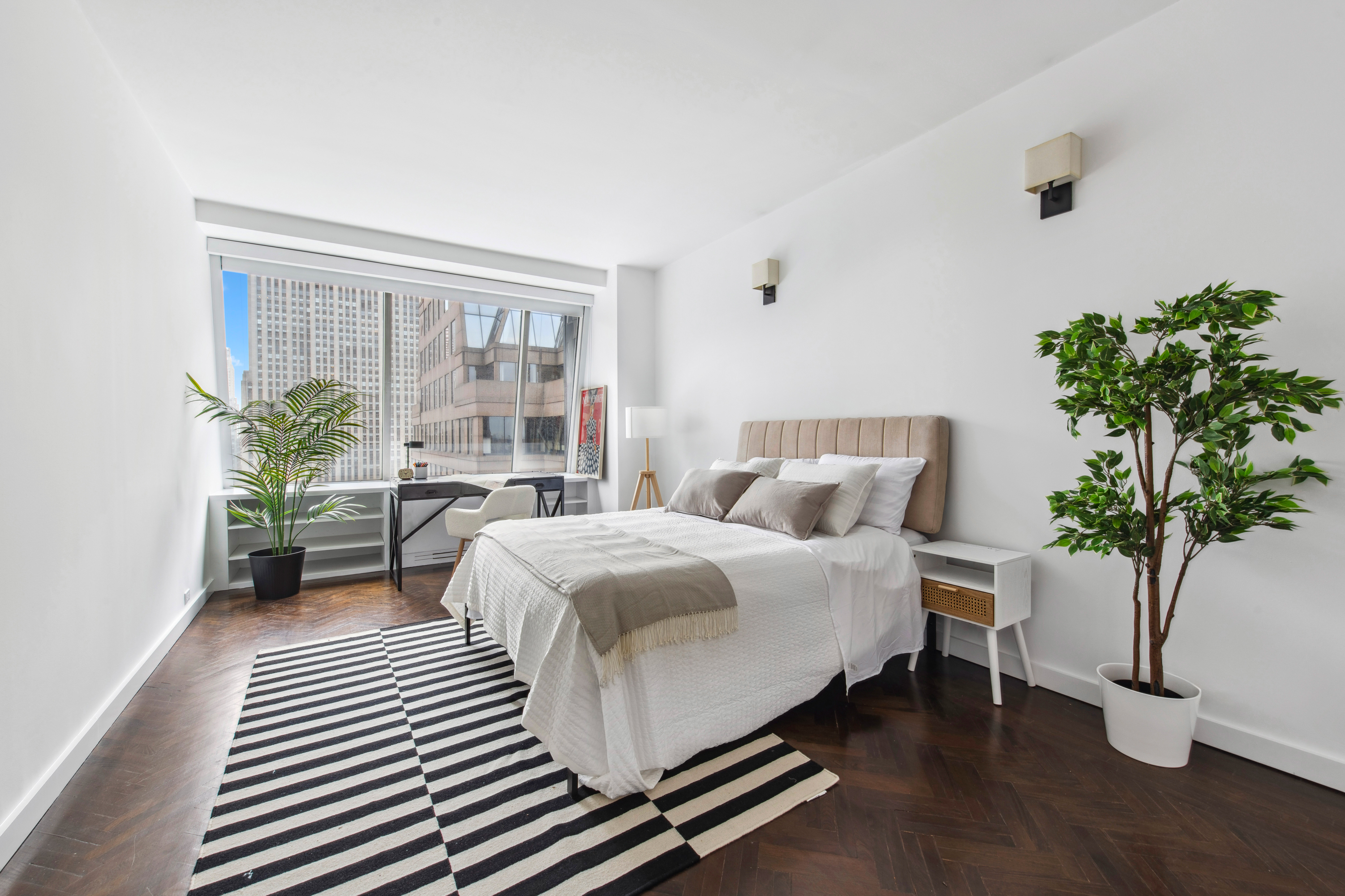 15 West 53rd Street, Unit 31C Manhattan, NY 10019 - Photo 3 of 14 a bed sitting in a bedroom next to a window with potted plant