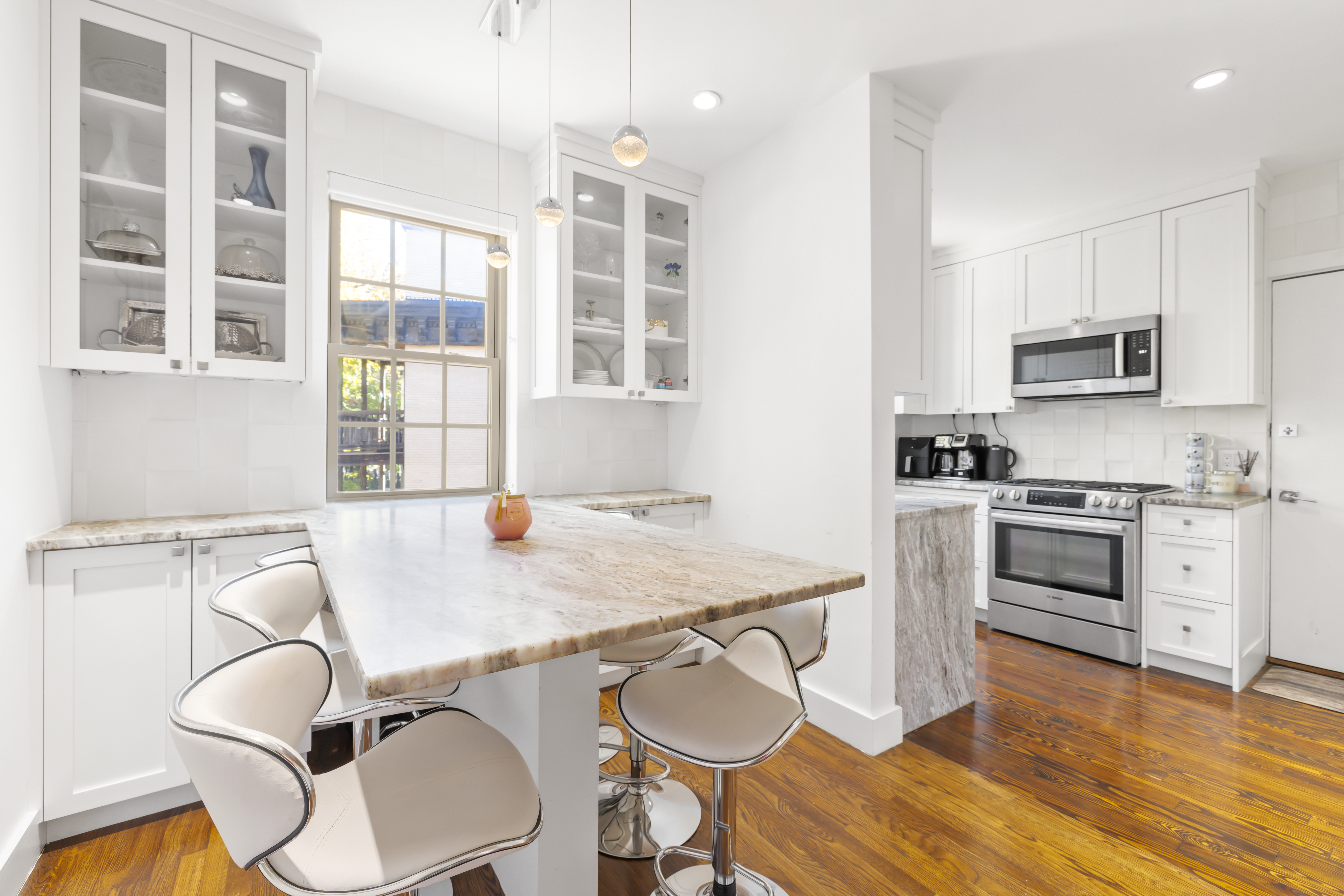 1490 Beacon Street, Unit 4 Brookline, MA 02446 - Photo 7 of 20 a kitchen with stainless steel appliances a stove a sink a microwave a dining table and chairs