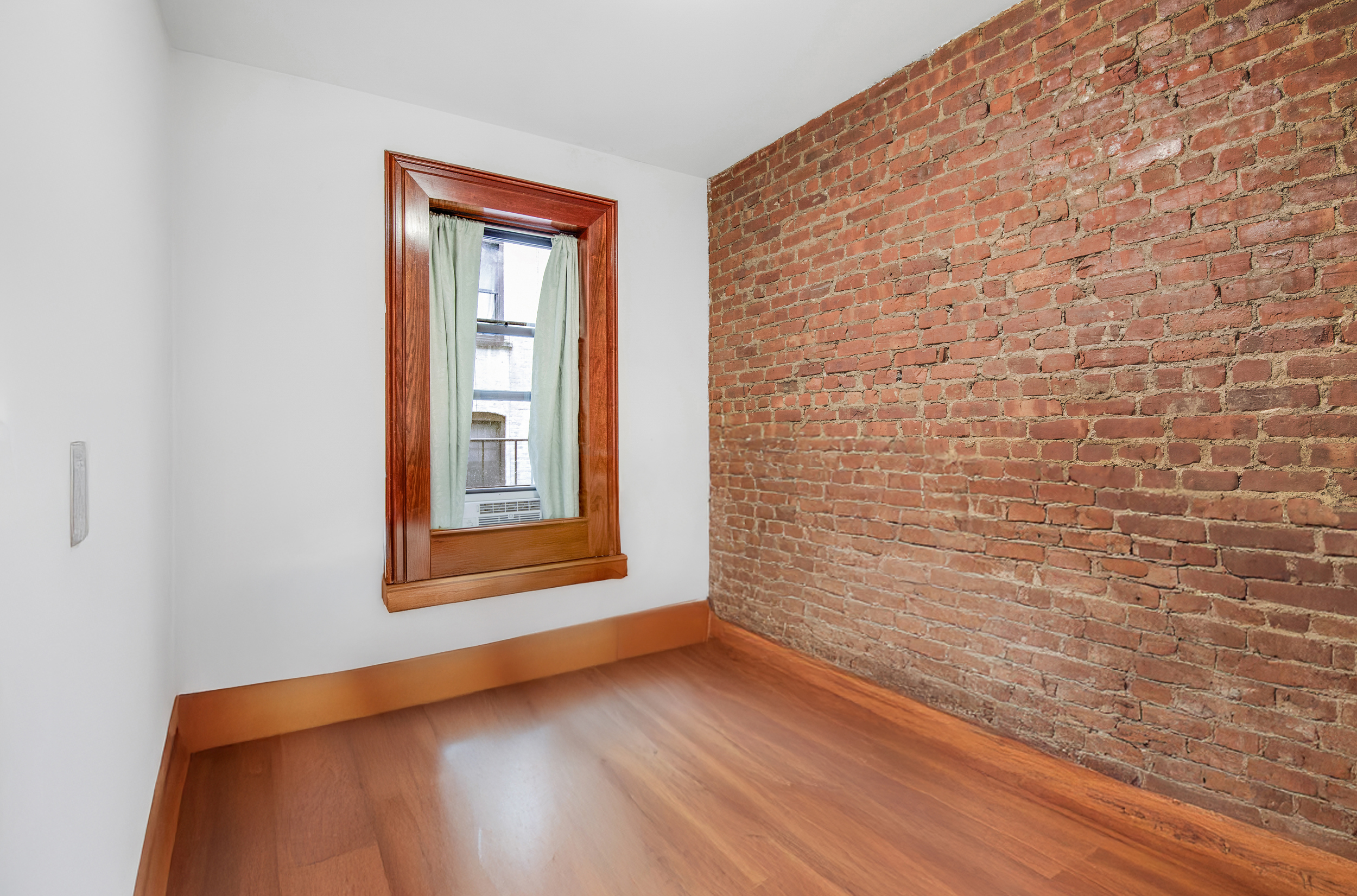 1392 Madison Avenue, Unit 28 Manhattan, NY 10128 - Photo 5 of 10 a view of an empty room with wooden floor and a window