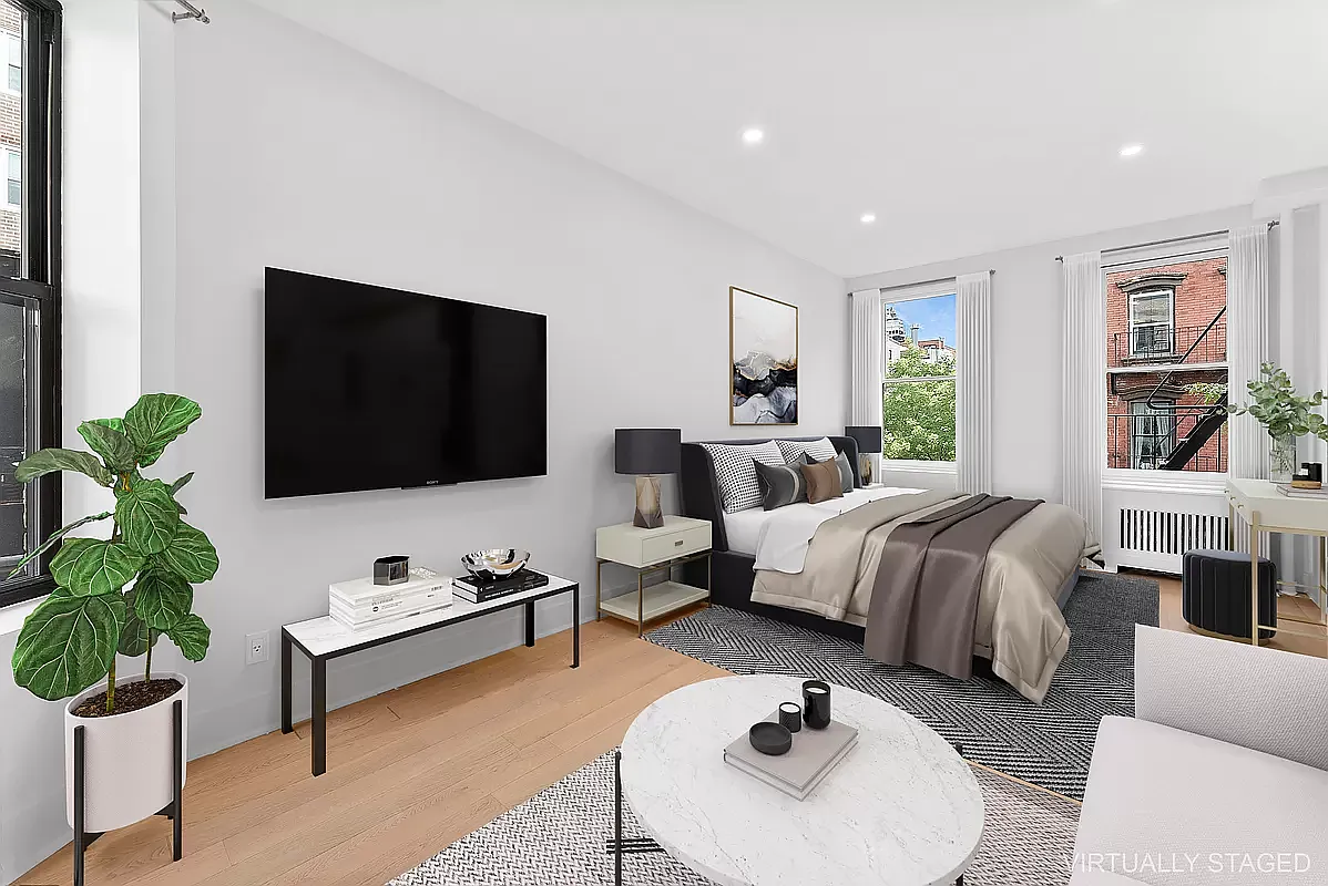 a spacious bedroom with a bed a couch and a potted plant