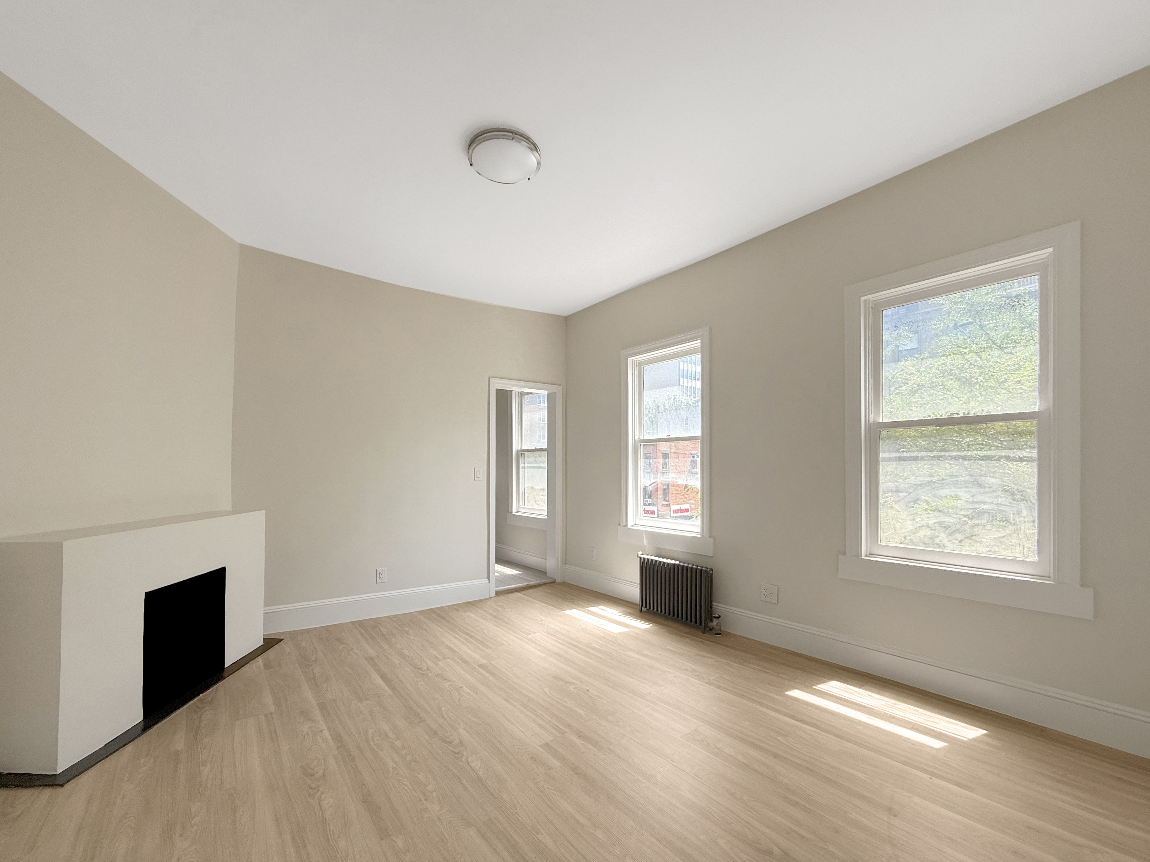 a view of an empty room with a window and wooden floor