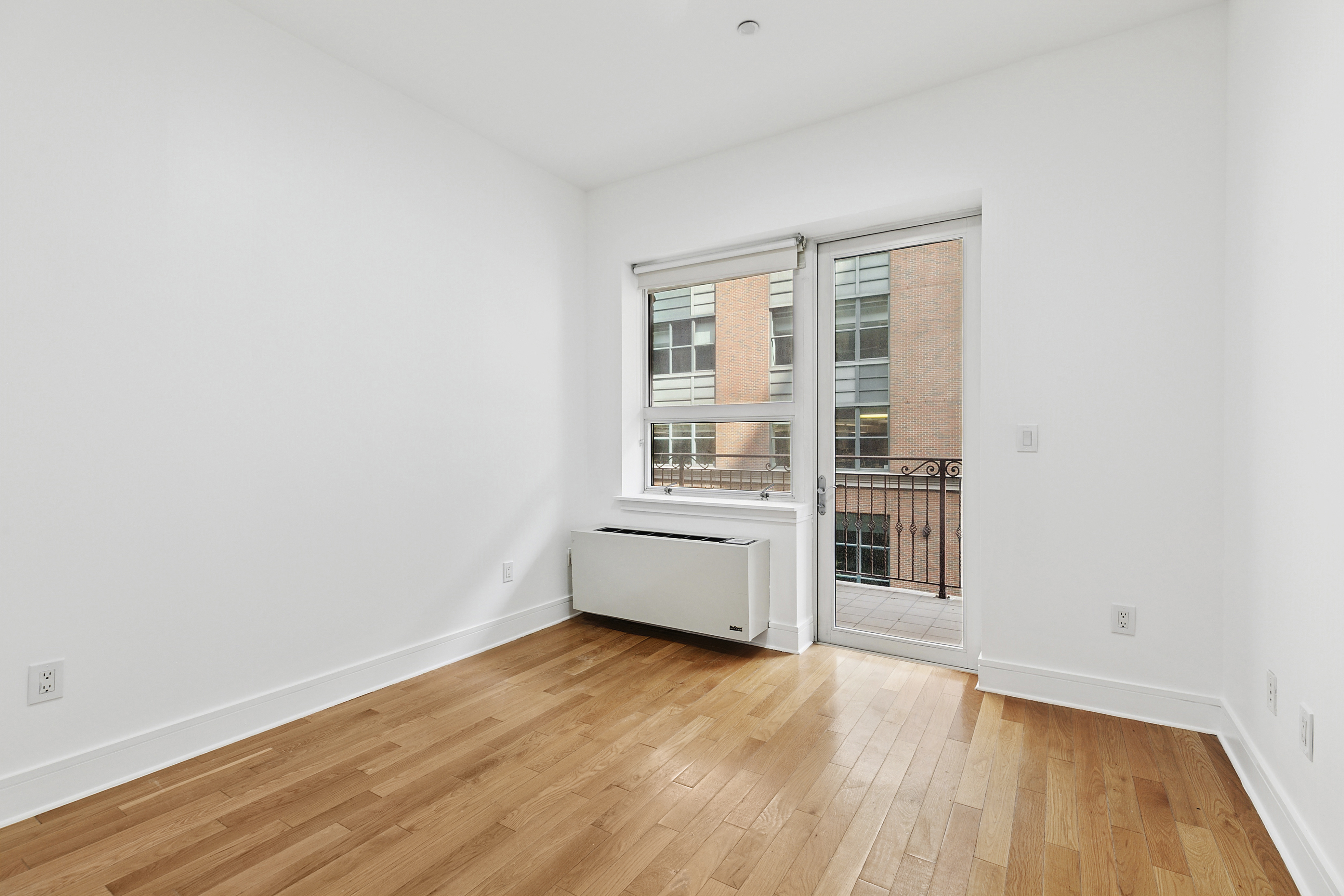 41-26 27th Street, Unit 4H Queens, NY 11101 - Photo 10 of 21 an empty room with wooden floor and windows