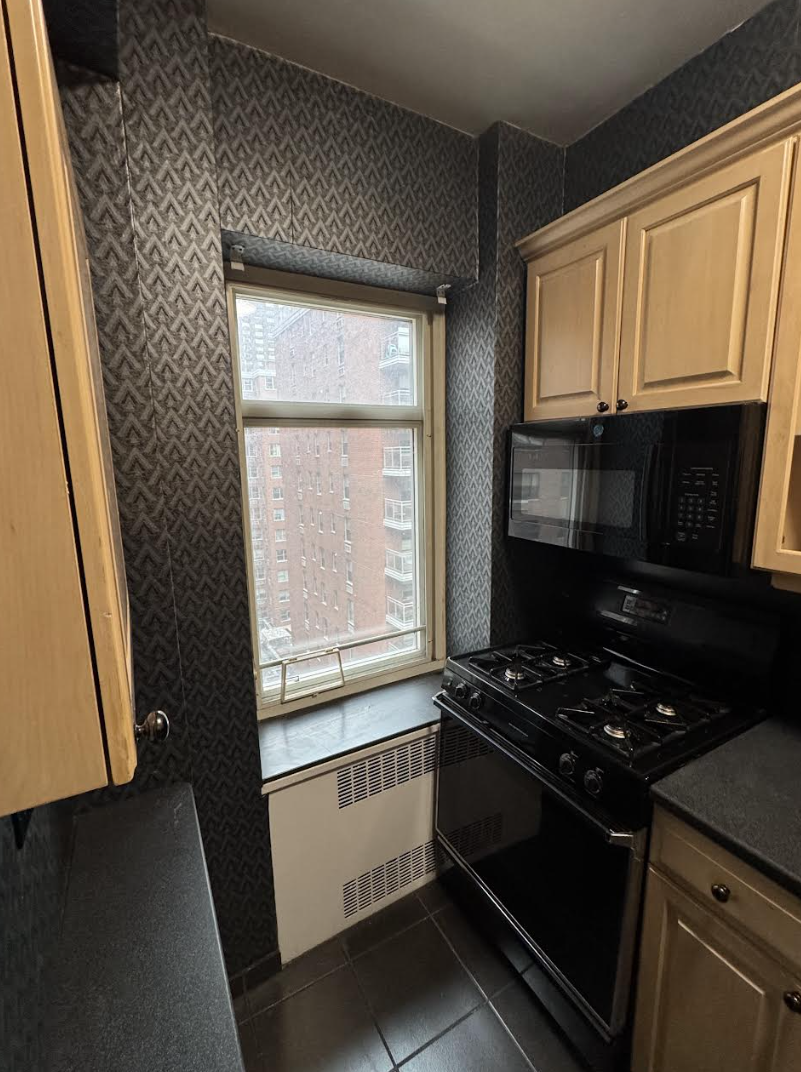 36 Sutton Place South, Unit 8E Manhattan, NY 10022 - Photo 3 of 7 a kitchen with granite countertop a stove and a microwave