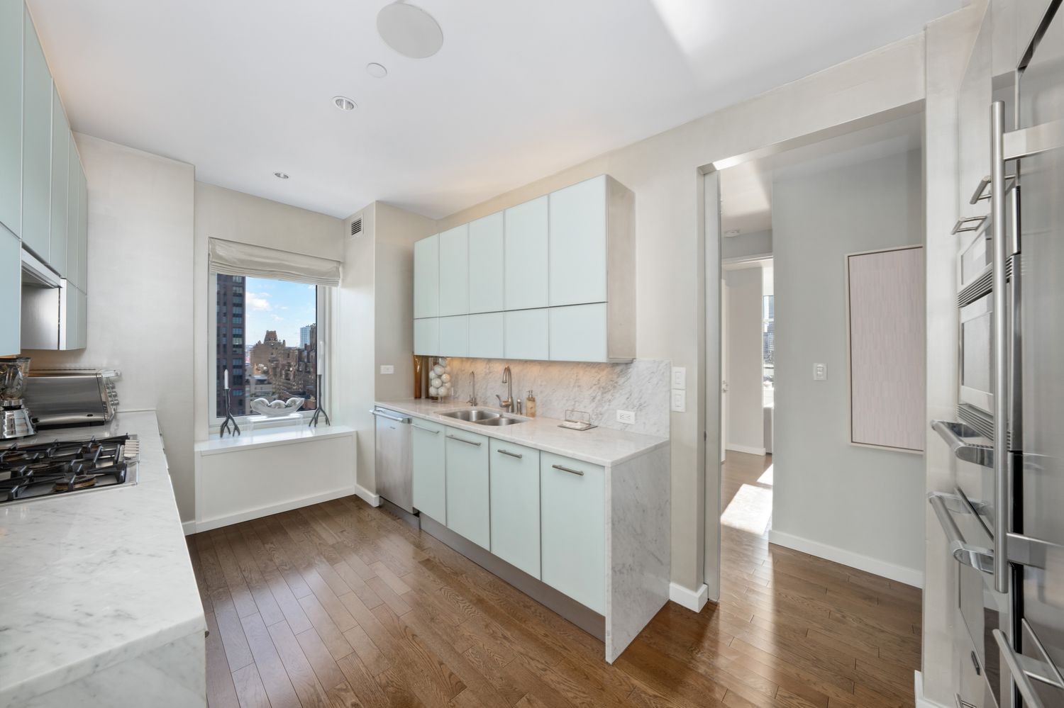 a large white kitchen with a sink stainless steel appliances and cabinets