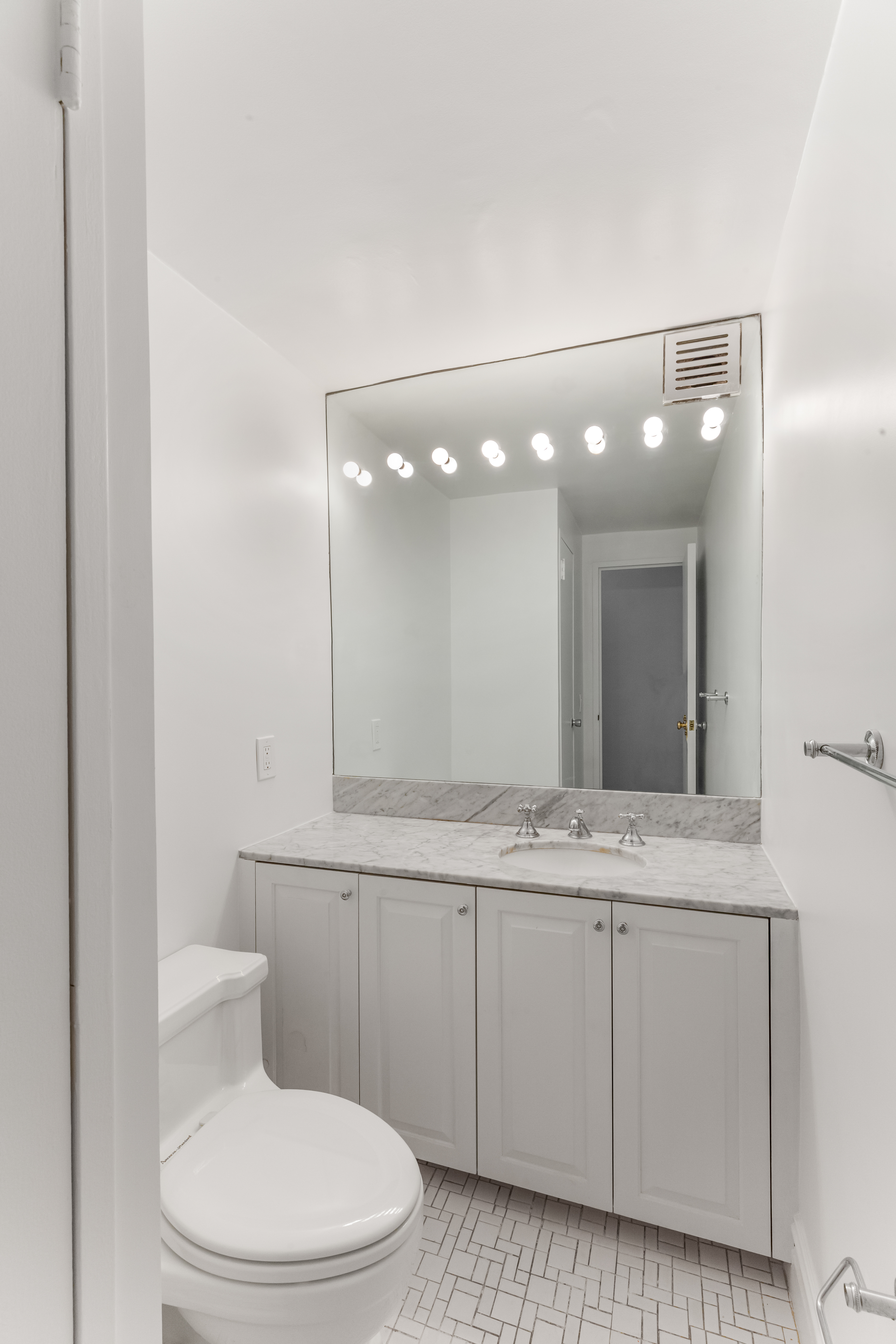175 East 62nd Street, Unit 10B Manhattan, NY 10065 - Photo 7 of 12 a bathroom with a sink a toilet and mirror