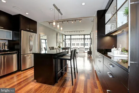 a kitchen with stainless steel appliances granite countertop a refrigerator a stove top oven a sink with island and chairs