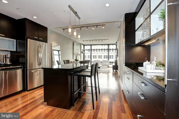 a kitchen with stainless steel appliances granite countertop a refrigerator a stove top oven a sink with island and chairs