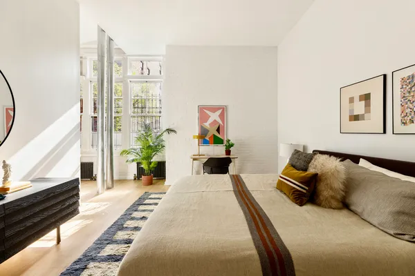 a bedroom with a bed a couch and potted plant on the dresser