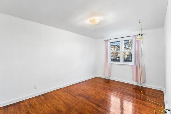an empty room with wooden floor and window