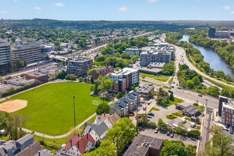 an aerial view of a city with lots of residential buildings ocean and mountain view in back