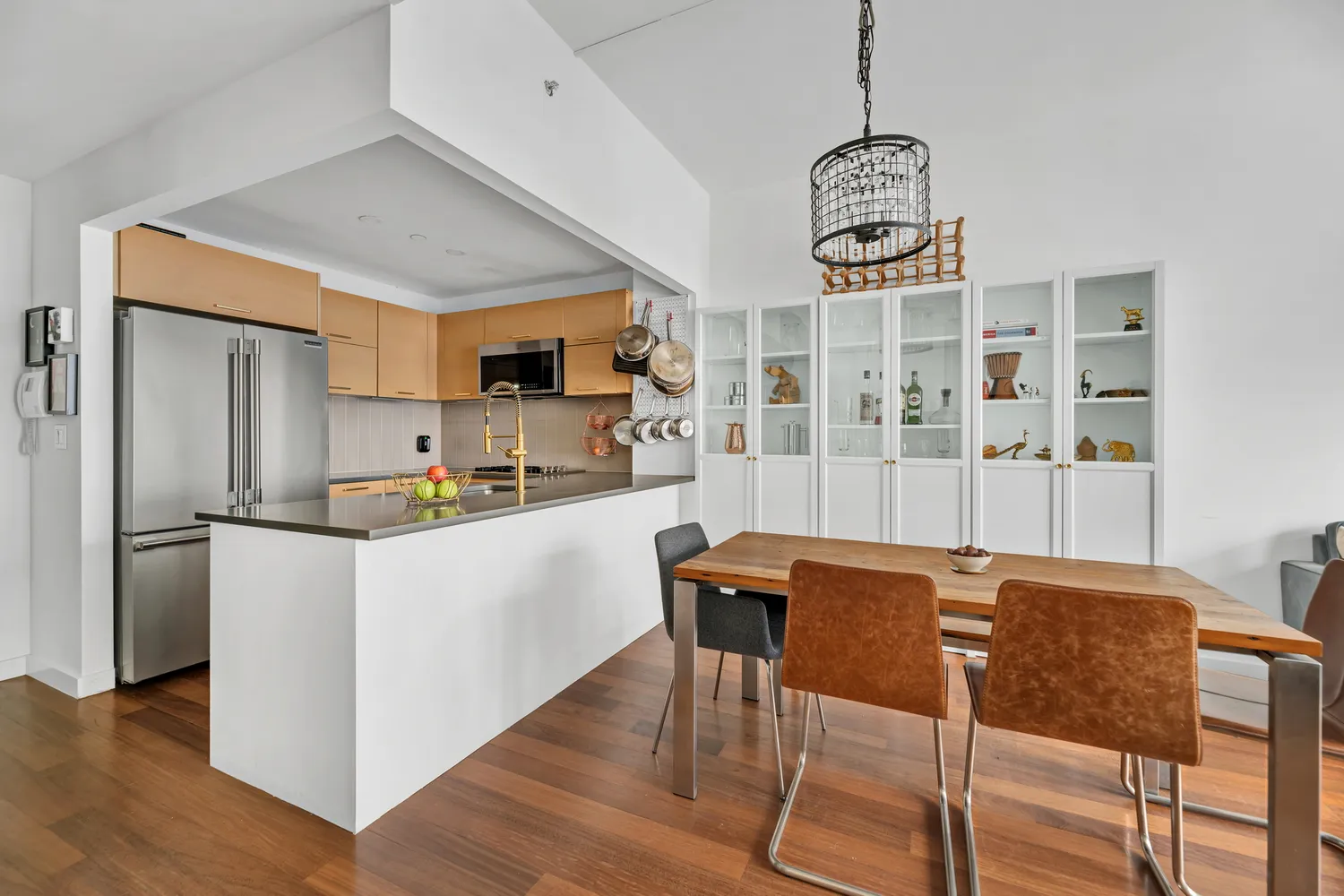 a kitchen with stainless steel appliances granite countertop a dining table chairs refrigerator and sink