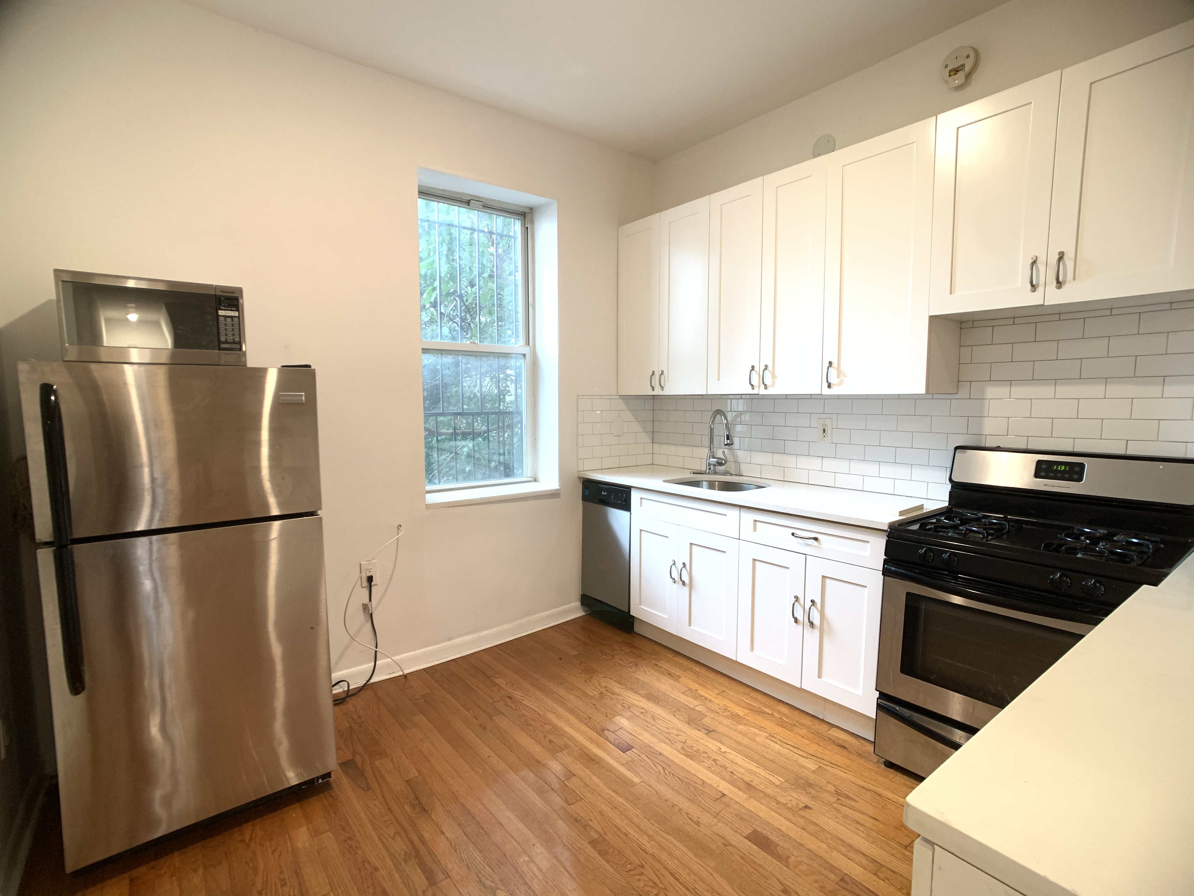 293 Tompkins Avenue Brooklyn, NY 11221 - Photo 9 of 19 a kitchen with a refrigerator stove and wooden cabinets