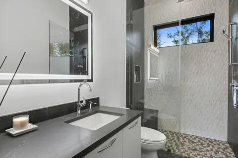 a bathroom with a granite countertop sink a toilet and a mirror