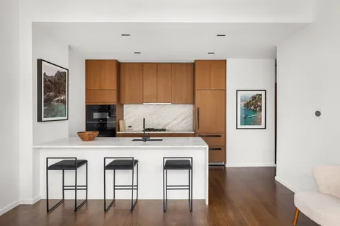 a kitchen with stainless steel appliances granite countertop a table chairs refrigerator and sink