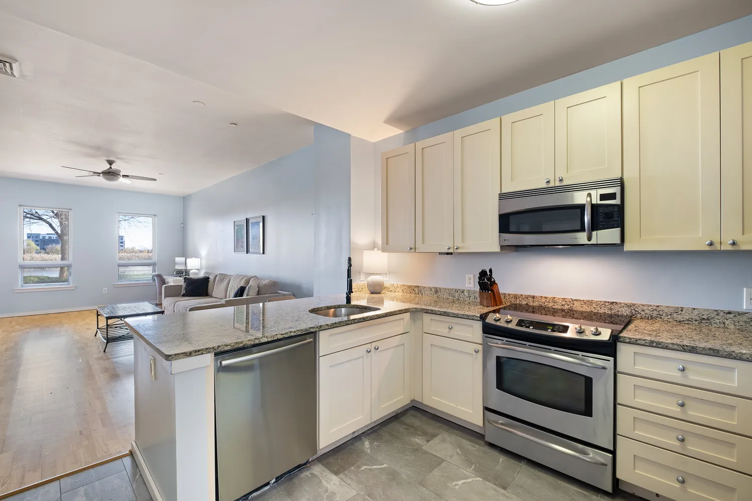 a kitchen with stainless steel appliances granite countertop a sink stove oven and white cabinets with wooden floor