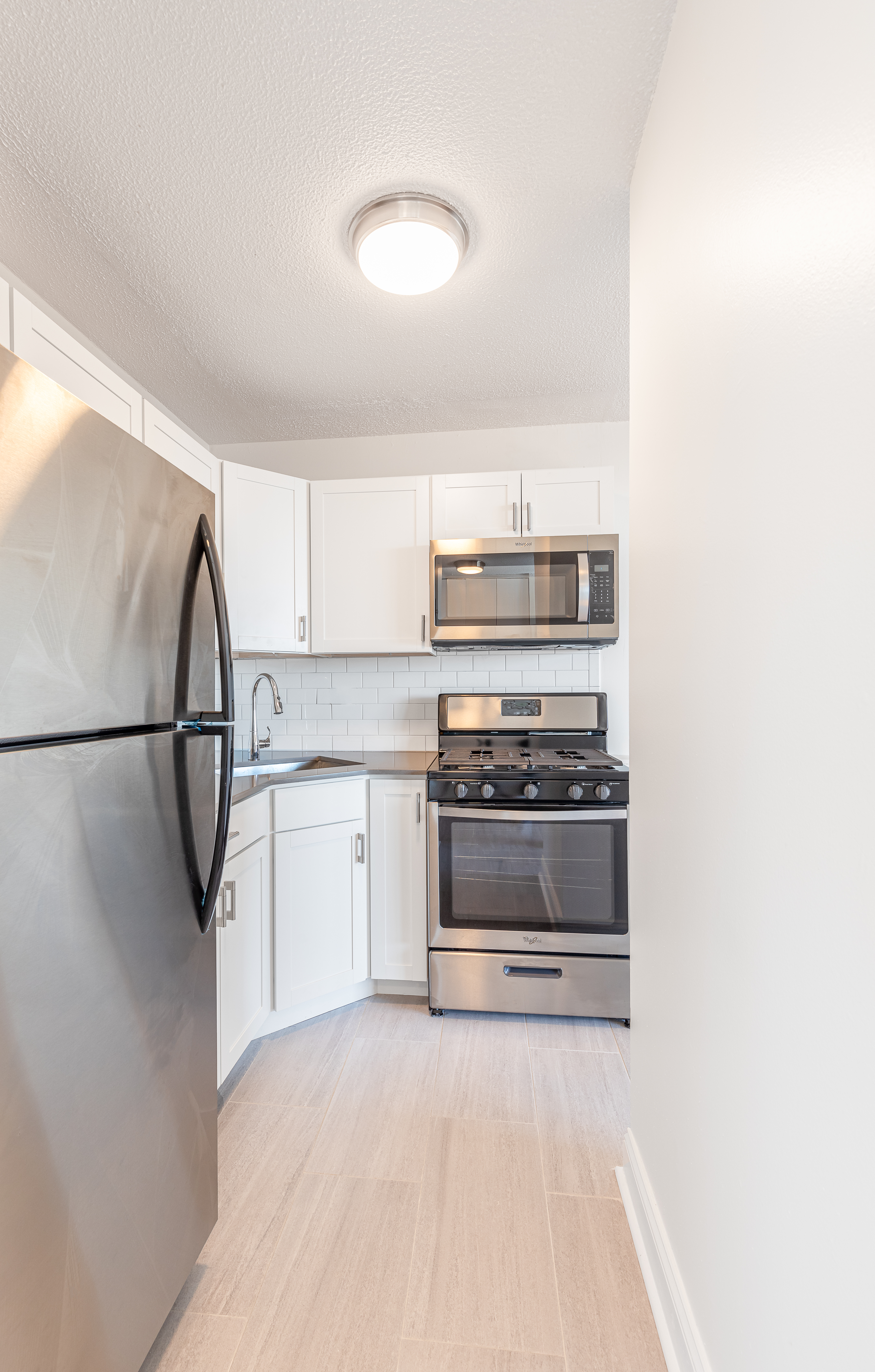 3333 Broadway, Unit C7K Manhattan, NY 10031 - Photo 4 of 21 a kitchen with white cabinets and stainless steel appliances