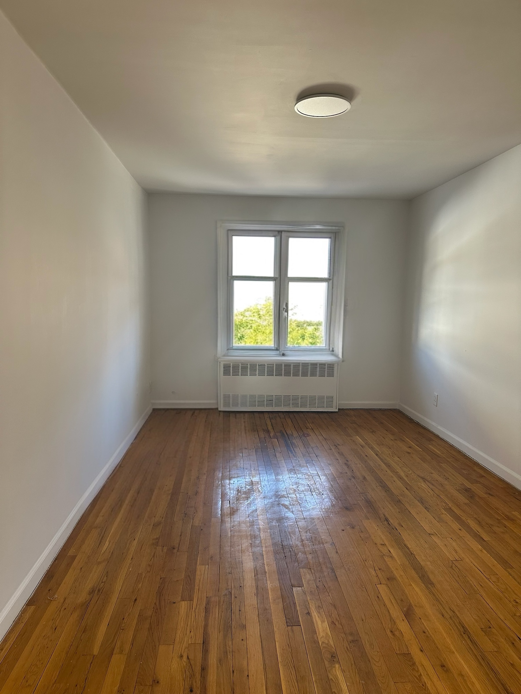 9823 Seaview Avenue, Unit 1 Brooklyn, NY 11236 - Photo 3 of 3 an empty room with wooden floor and windows