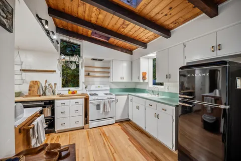 a kitchen with stainless steel appliances a stove a sink dishwasher and cabinets with wooden floor
