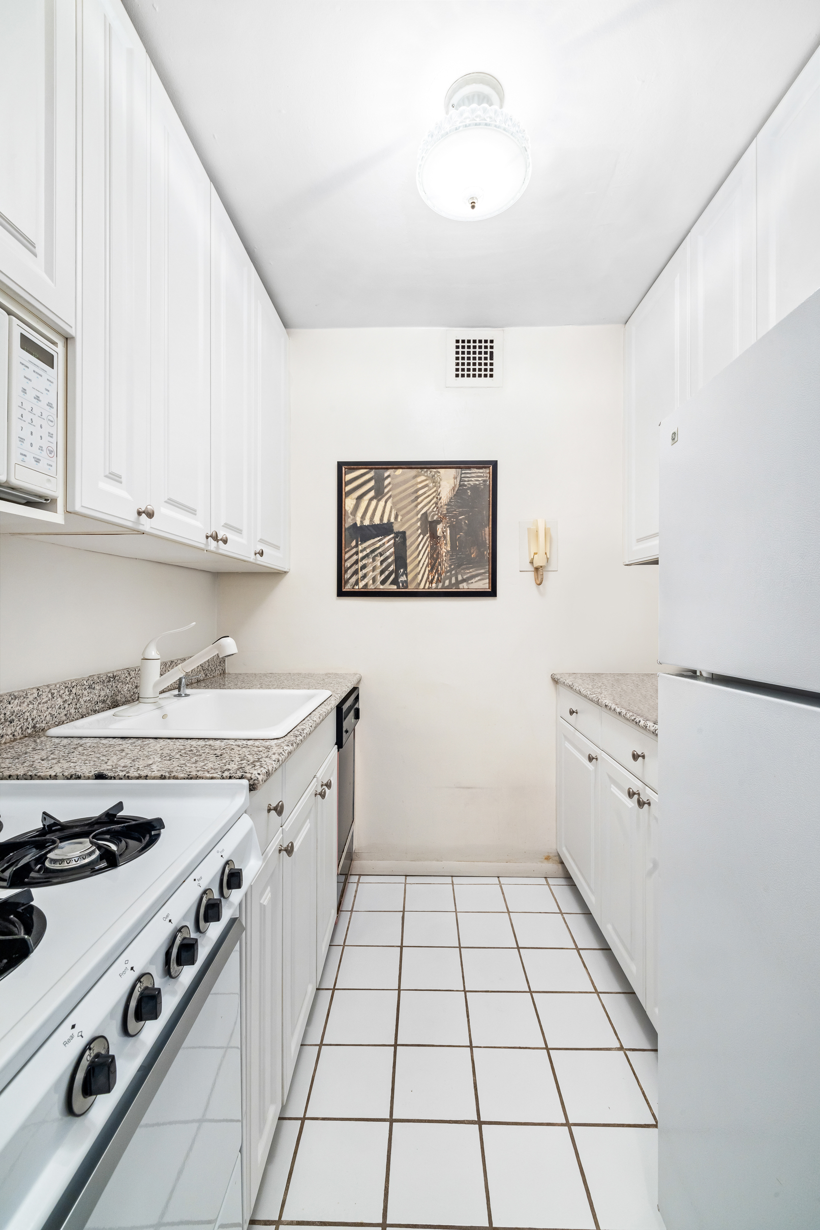 166 East 61st Street, Unit 8H Manhattan, NY 10065 - Photo 4 of 9 a kitchen with a stove cabinets and window