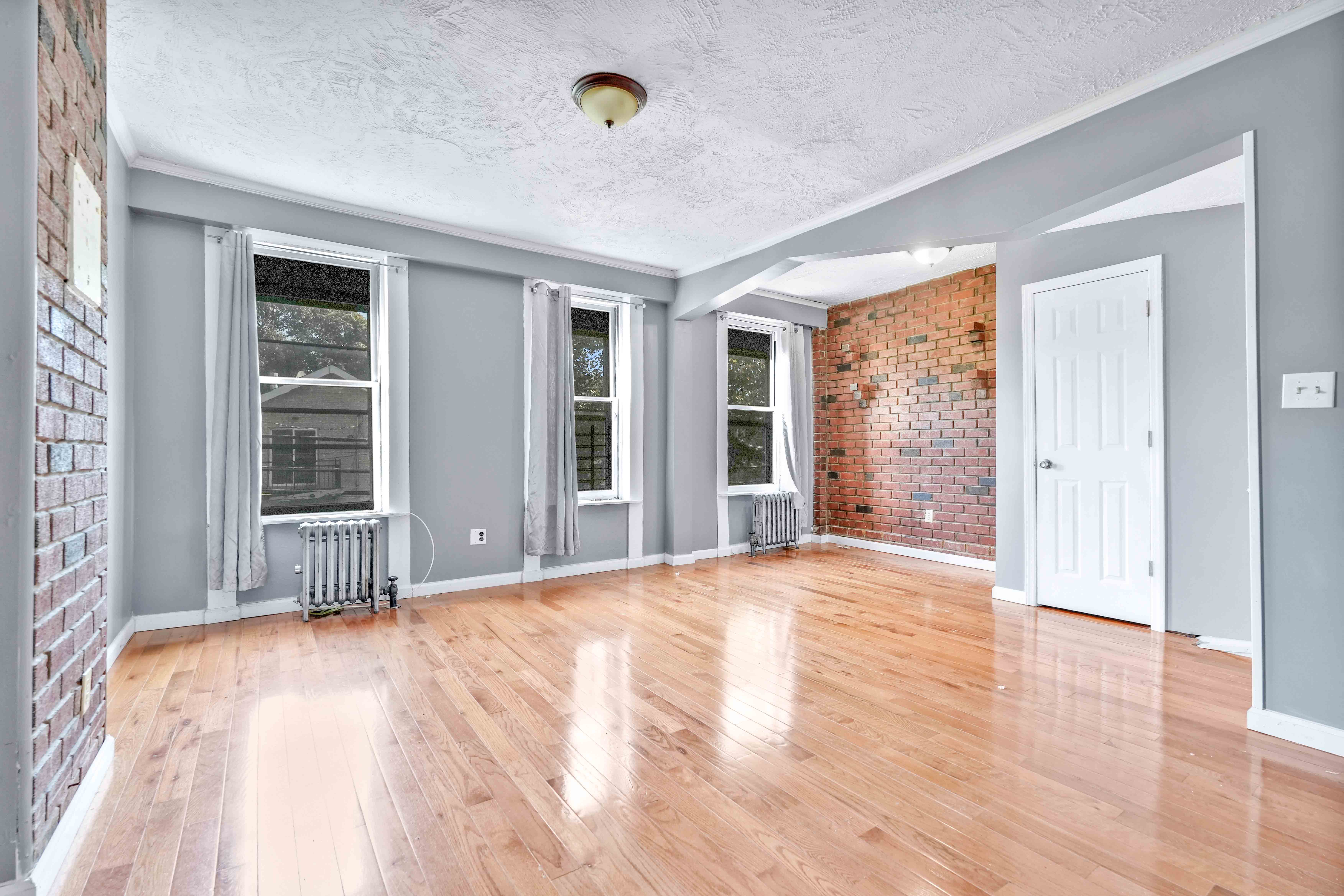 610 Ashford Street Brooklyn, NY 11207 - Photo 3 of 28 a view of an empty room with wooden floor and windows