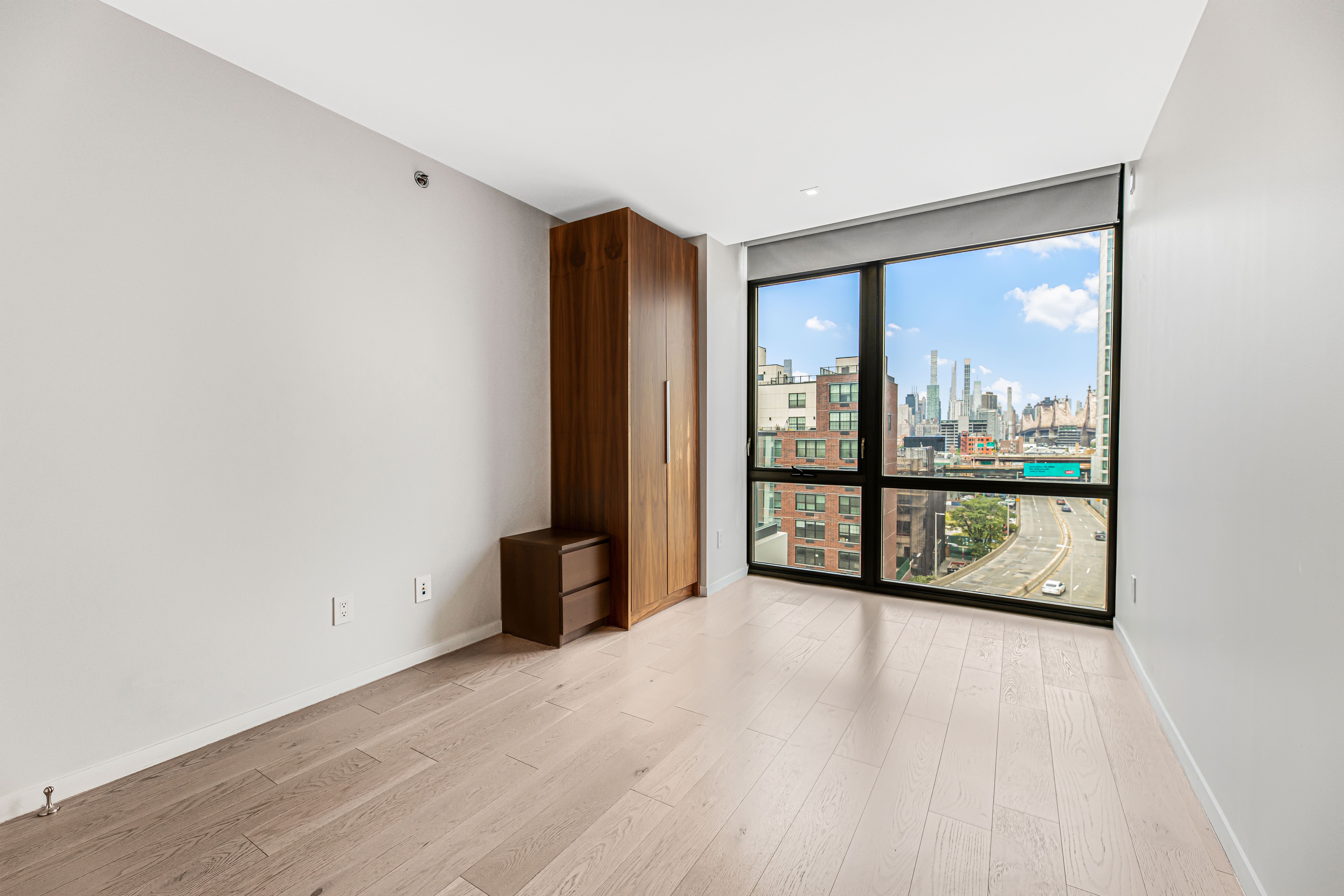 42-50 27th Street, Unit 9C Queens, NY 11101 - Photo 4 of 32 wooden floor in an empty room with a window