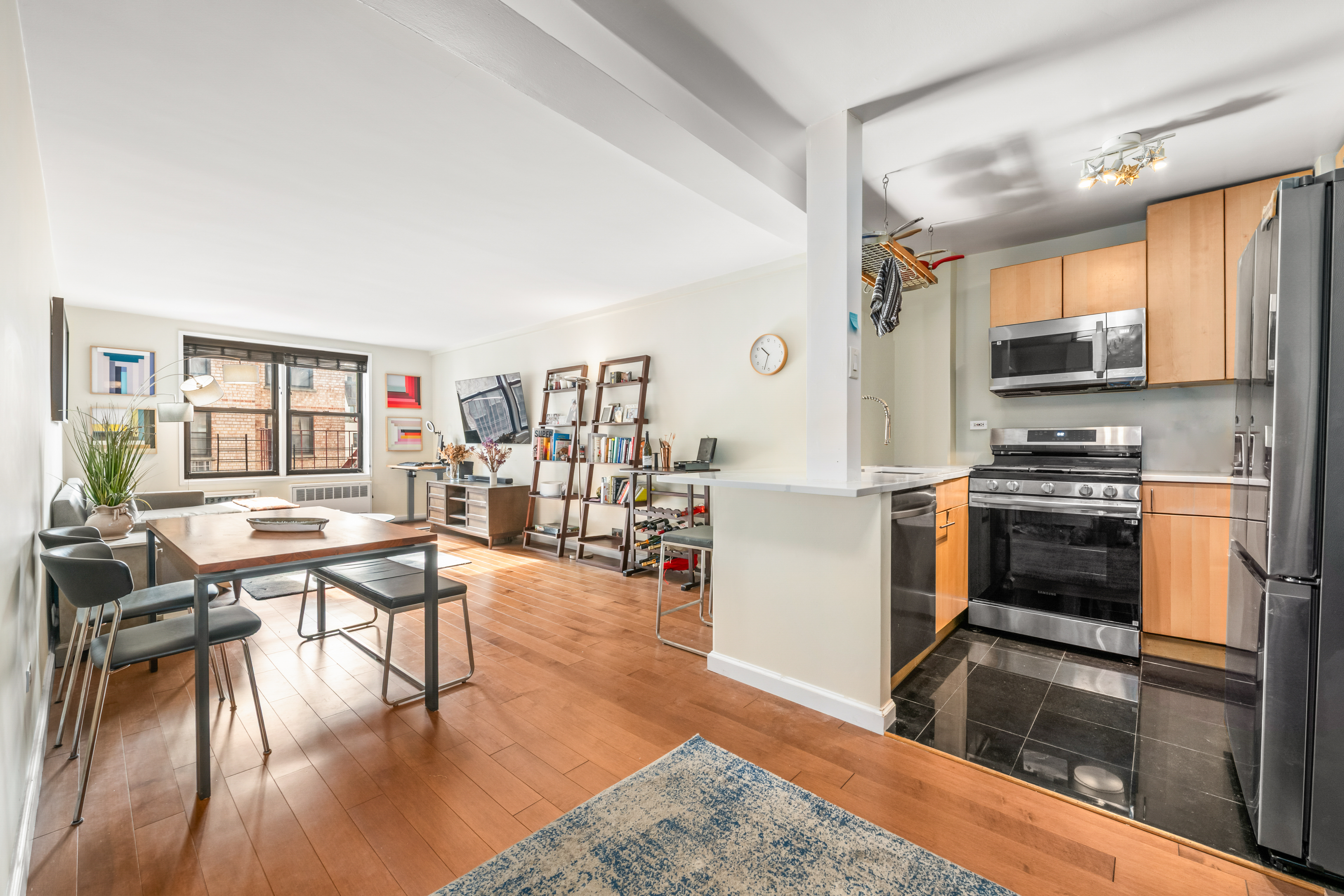 165 Christopher Street, Unit 5AA Manhattan, NY 10014 - Photo 3 of 9 a kitchen with stainless steel appliances granite countertop a stove top oven a sink a dining table and chairs with wooden floor