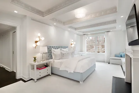 a bedroom with bed and a flat tv screen on dresser