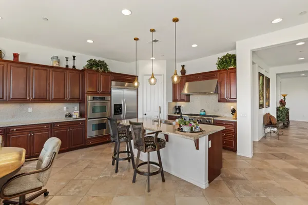 a kitchen with stainless steel appliances granite countertop a sink a stove and a wooden floors