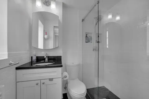 a bathroom with a toilet sink vanity and mirror