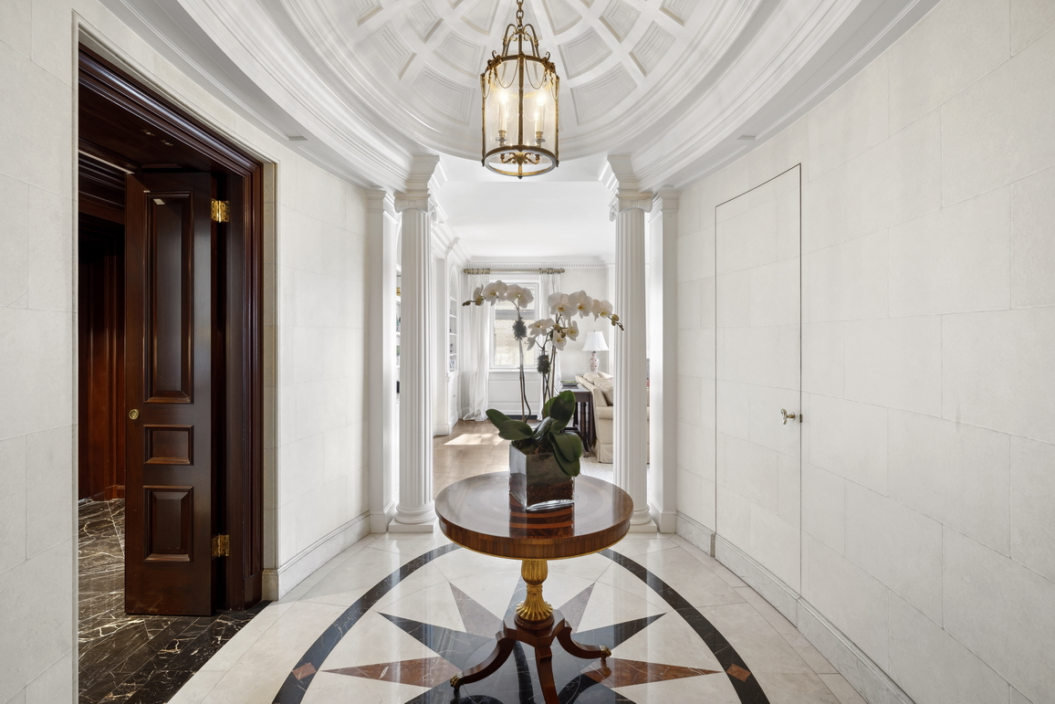 875 5th Avenue, Unit 18A Manhattan, NY 10065 - Photo 8 of 14 a view of a hallway with wooden floor and a chandelier