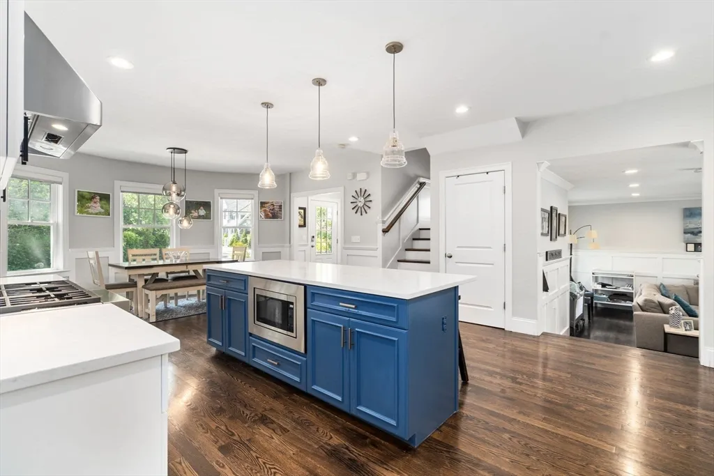 a kitchen with stainless steel appliances kitchen island granite countertop a stove a sink and a wooden floor