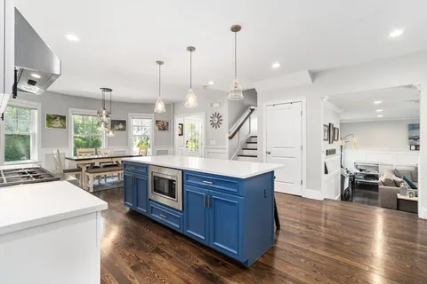 a kitchen with stainless steel appliances kitchen island granite countertop a stove a sink and a wooden floor