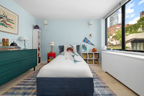a bedroom with a bed a large window and baby crib