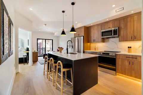 a kitchen with stainless steel appliances granite countertop a stove top oven a sink a dining table and chairs with wooden floor