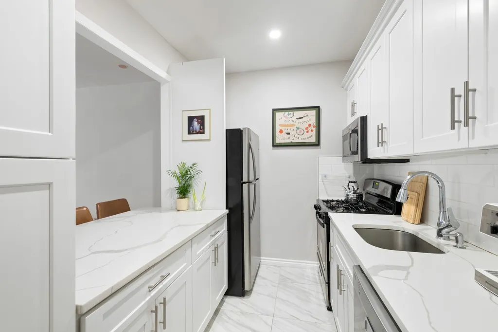 a kitchen with stainless steel appliances a sink a stove a refrigerator a counter top space and cabinets