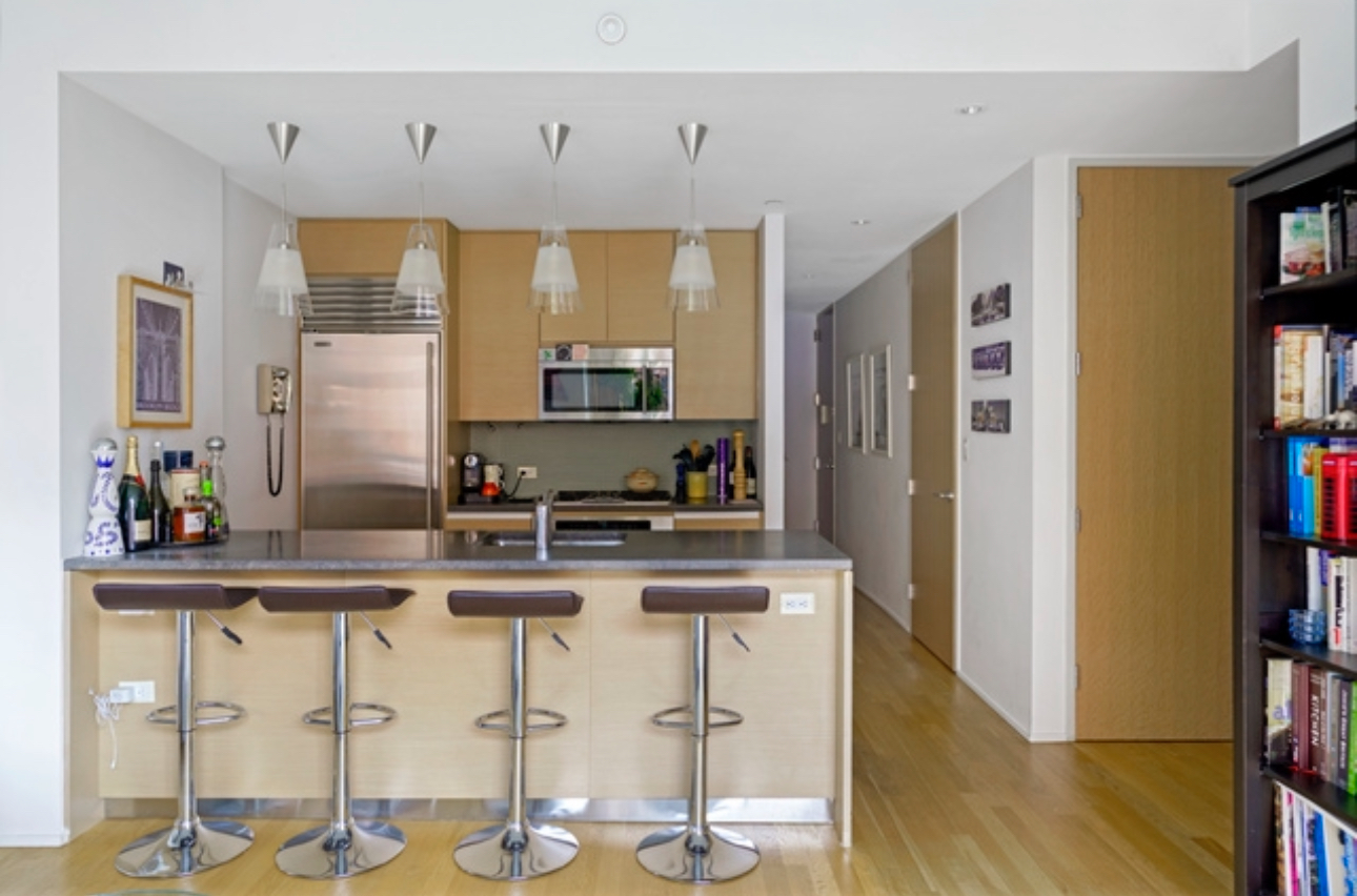 110 3rd Avenue, Unit 9B Manhattan, NY 10003 - Photo 2 of 14 a kitchen with stainless steel appliances granite countertop a stove a refrigerator a sink a dining table and chairs with wooden floor
