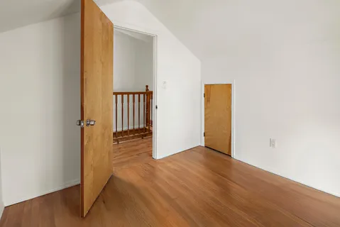 an empty room with wooden floor and hallway