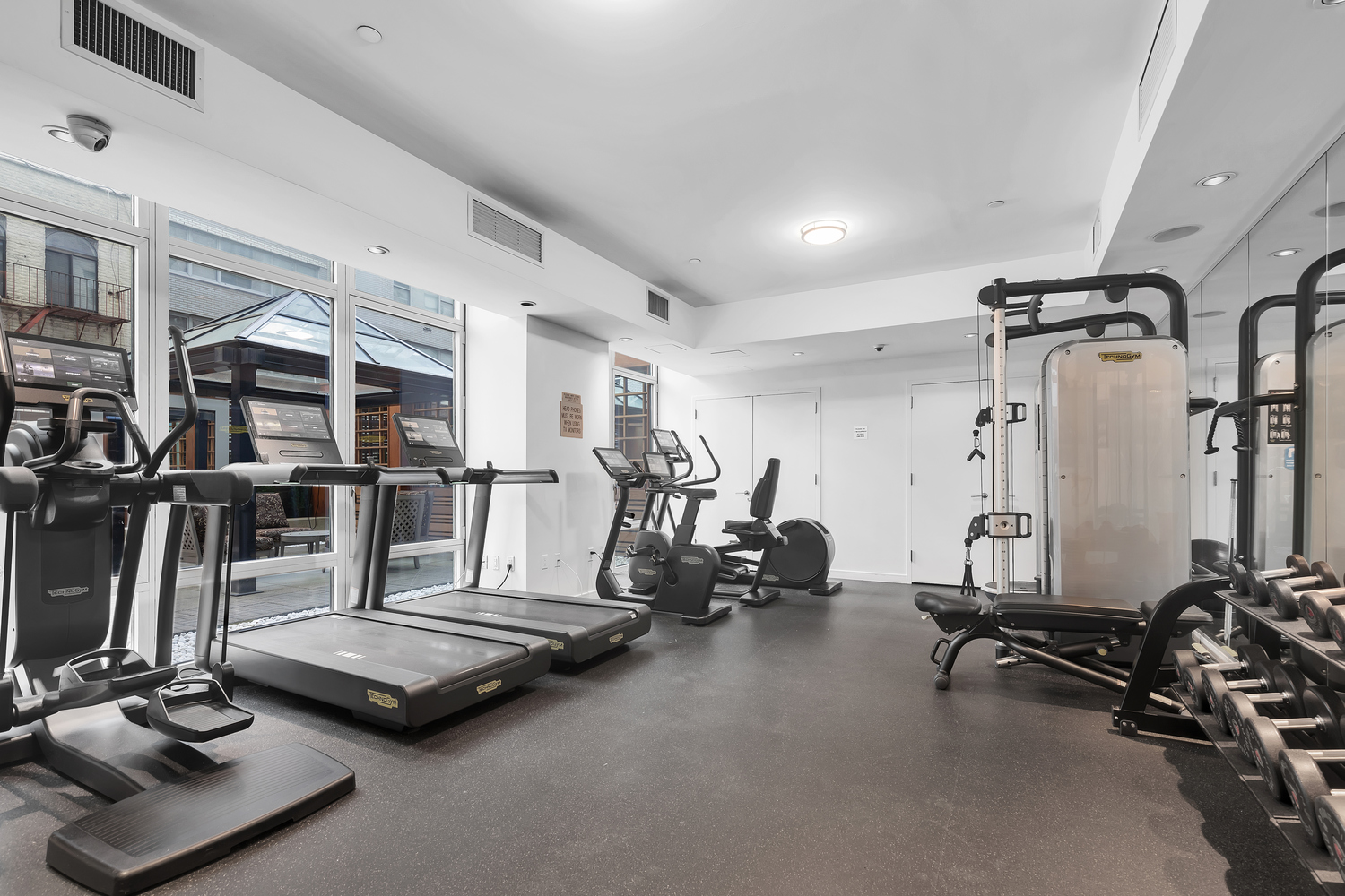 207 East 57th Street, Unit 25B Manhattan, NY 10022 - Photo 15 of 19 a room with gym equipment and large mirror