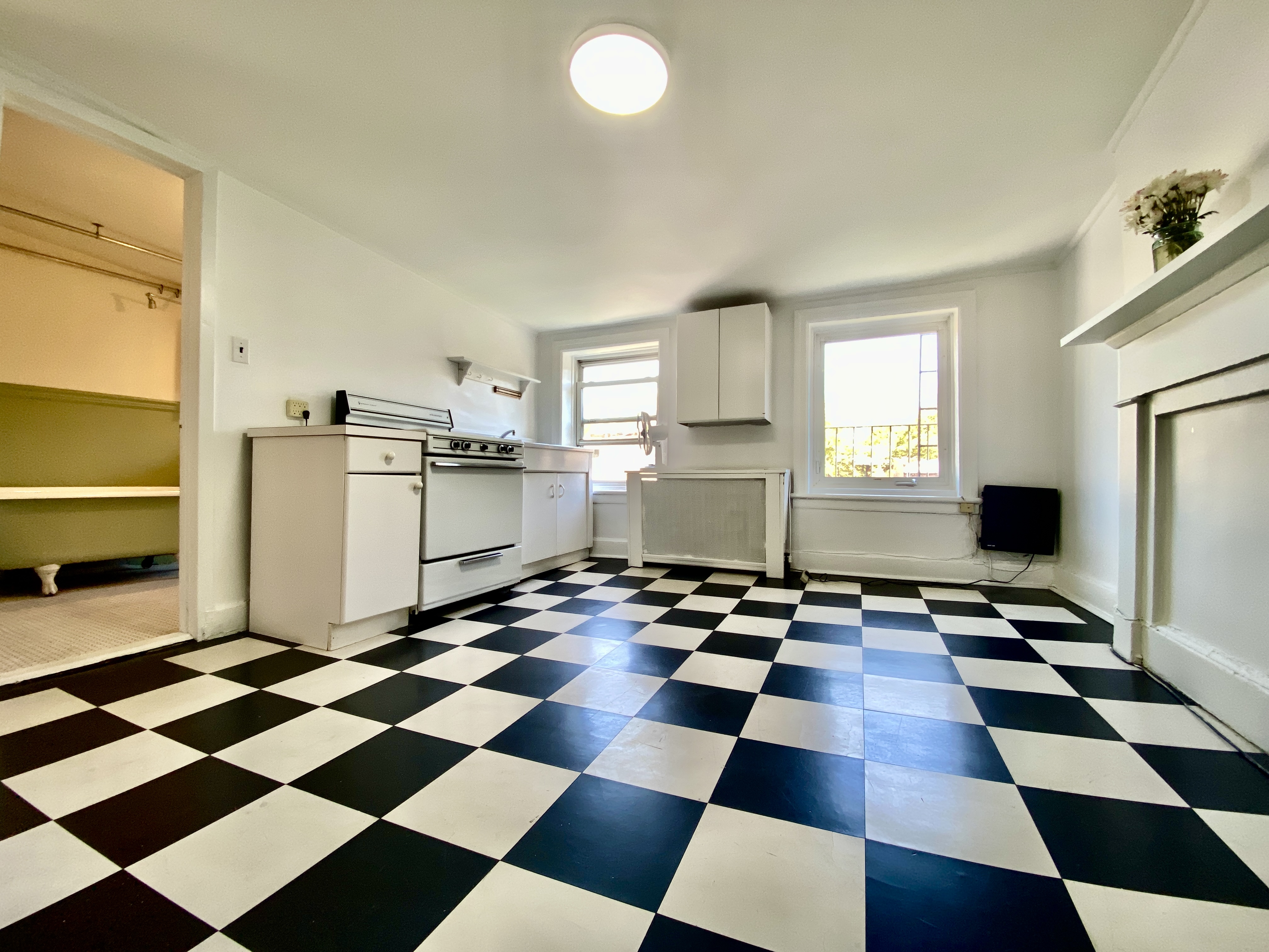 277 Warren Street, Unit 4 Brooklyn, NY 11201 - Photo 3 of 7 a room with a black white checkered floor with a gaming machine and appliances