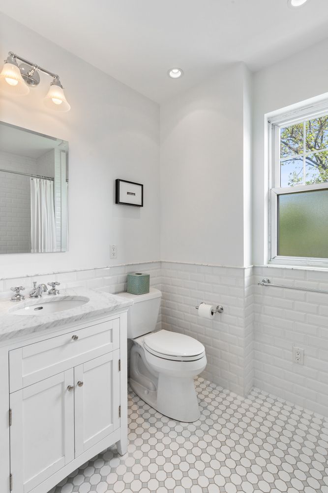685 East 22nd Street Brooklyn, NY 11210 - Photo 22 of 43 a bathroom with a toilet a sink a mirror a window and vanity
