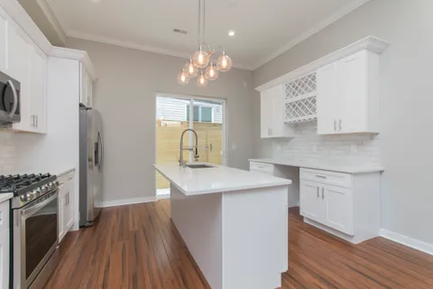 a kitchen with kitchen island white cabinets appliances and wooden floor