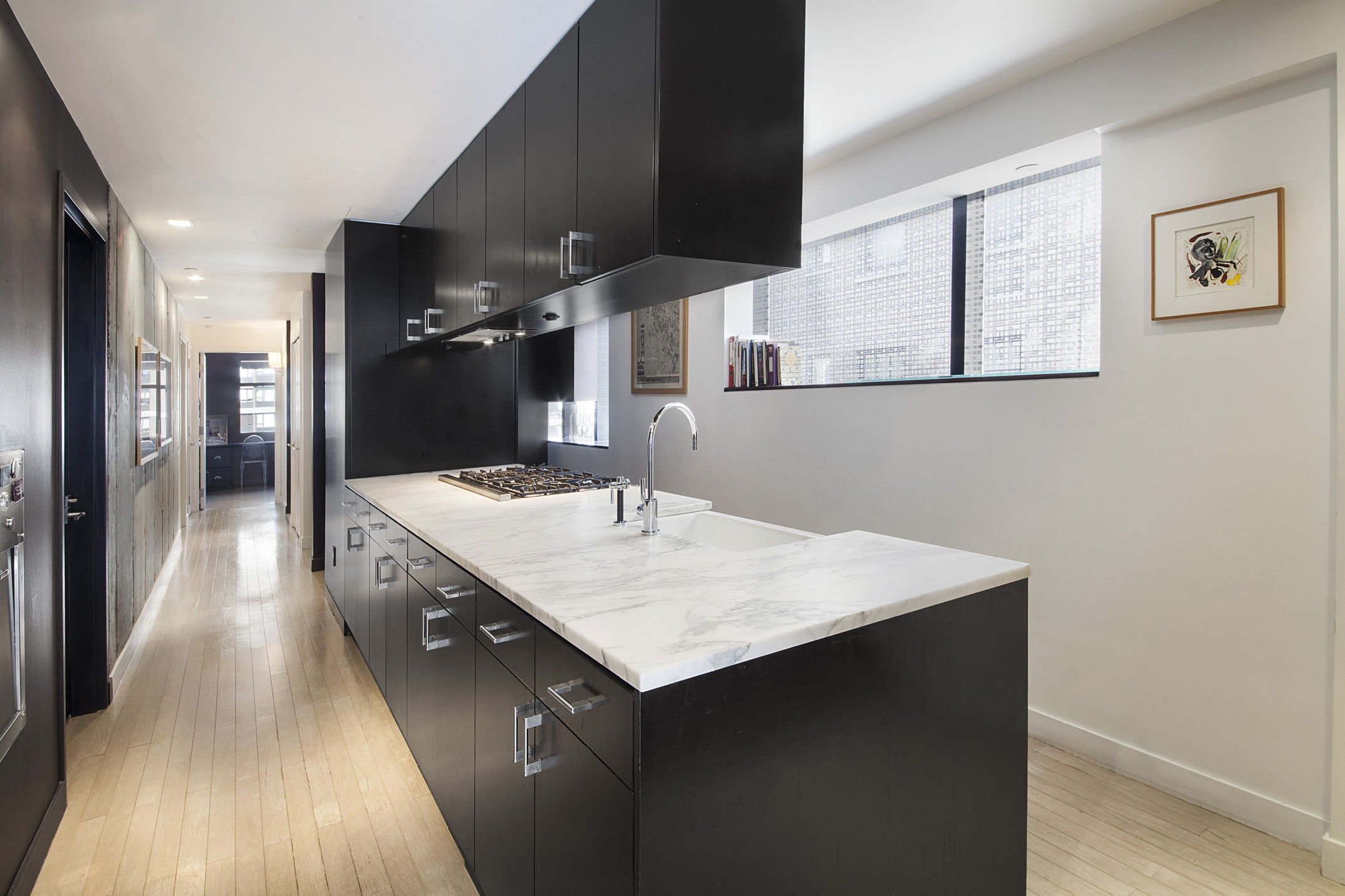 441 East 57th Street, Unit 5 Manhattan, NY 10022 - Photo 3 of 7 a hall with kitchen island a sink dishwasher a stove and a refrigerator with wooden floor
