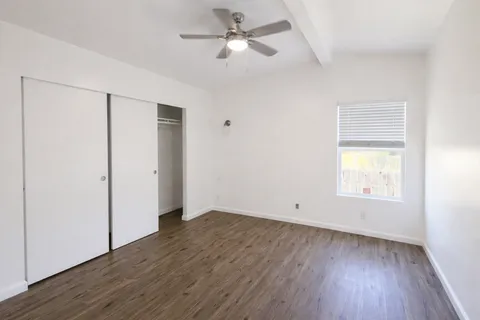 a view of empty room with wooden floor and fan