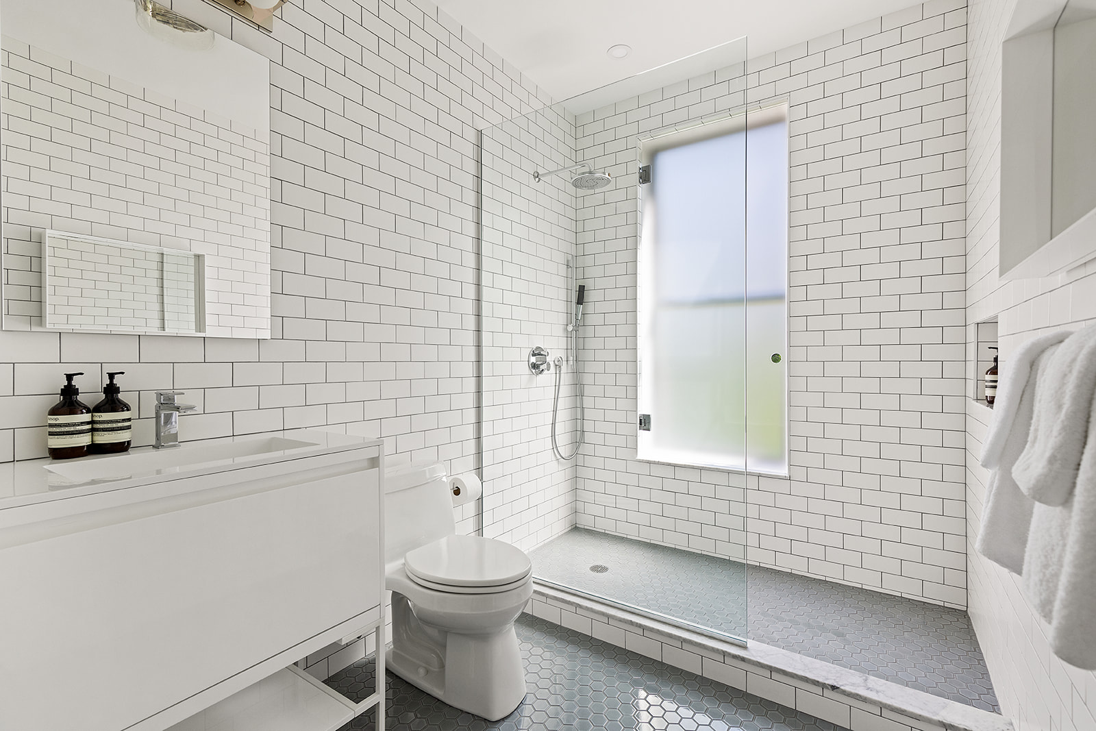 315 Adelphi Street, Unit 2 Brooklyn, NY 11205 - Photo 6 of 12 a bathroom with a granite countertop toilet a sink a mirror and shower