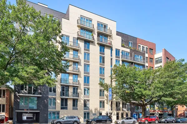 a front view of a building with lot of trees