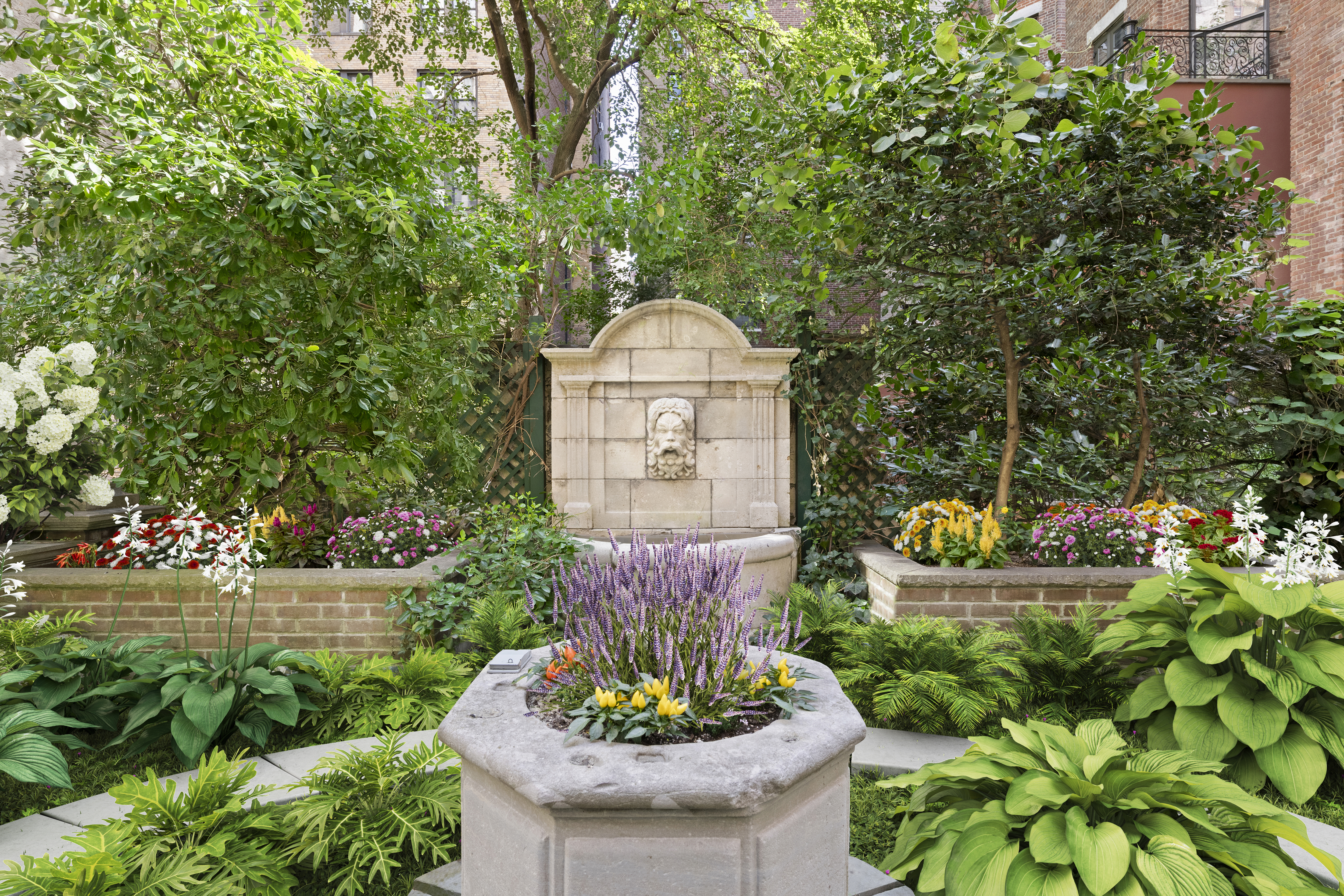 313 West 102nd Street Manhattan, NY 10025 - Photo 22 of 36 a front view of a house with a yard and fountain in middle