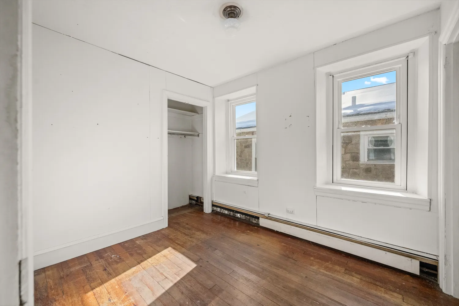 an empty room with wooden floor and windows