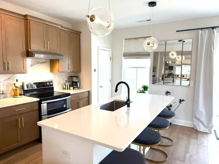 a large kitchen with stainless steel appliances a stove a sink a center island and cabinets